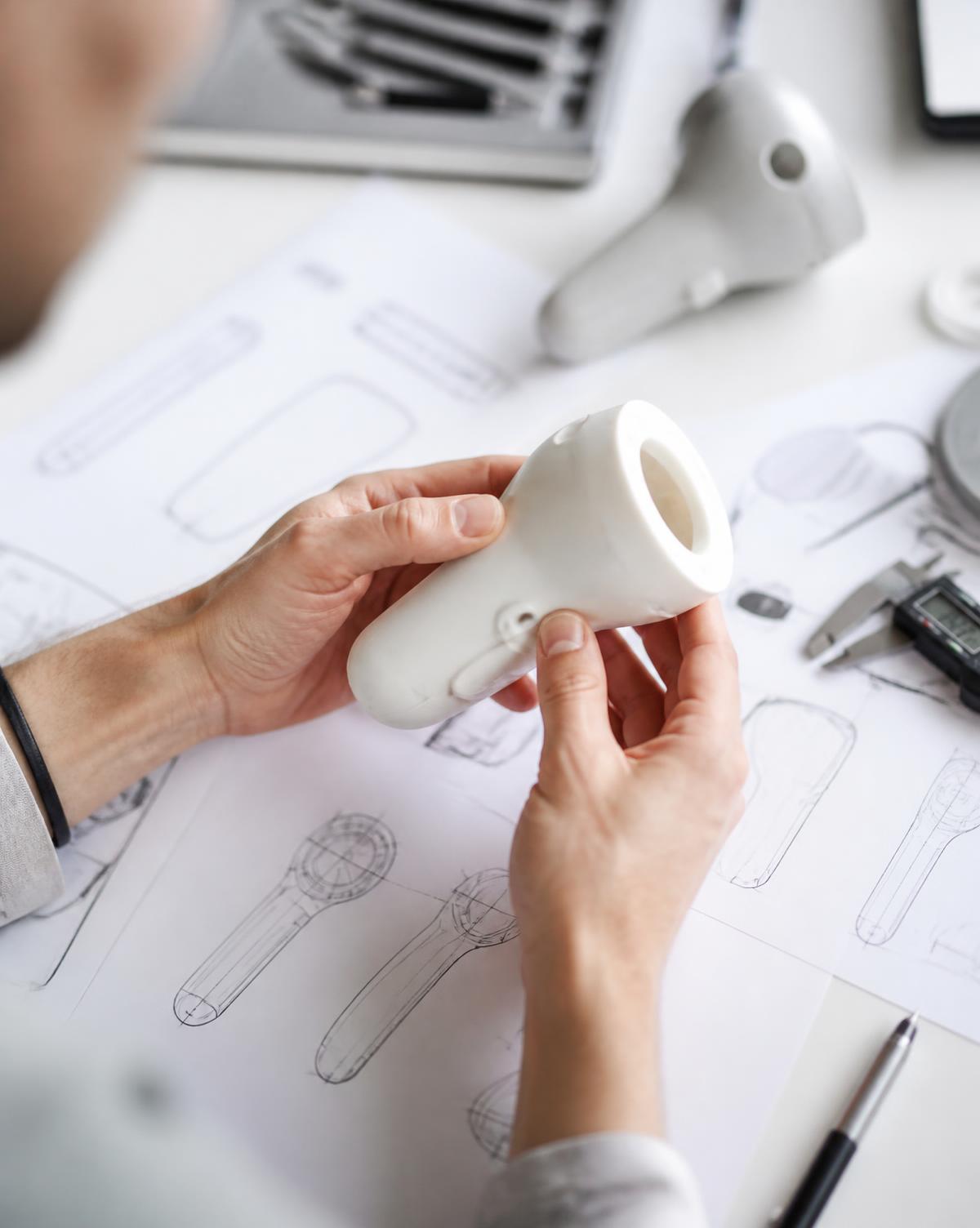 Diseño e ingeniería de producto plástico sobre mesa de trabajo con planos técnicos
